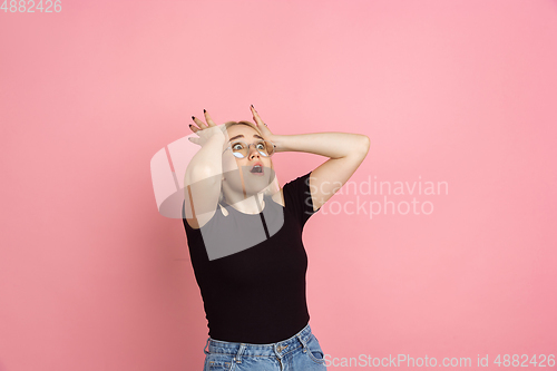 Image of Portrait of young caucasian woman with bright emotions on coral pink studio background