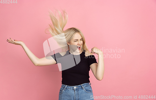 Image of Portrait of young caucasian woman with bright emotions on coral pink studio background