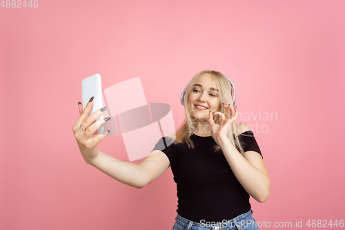 Image of Portrait of young caucasian woman with bright emotions on coral pink studio background