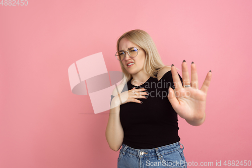 Image of Portrait of young caucasian woman with bright emotions on coral pink studio background