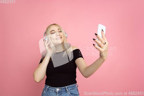 Image of Portrait of young caucasian woman with bright emotions on coral pink studio background