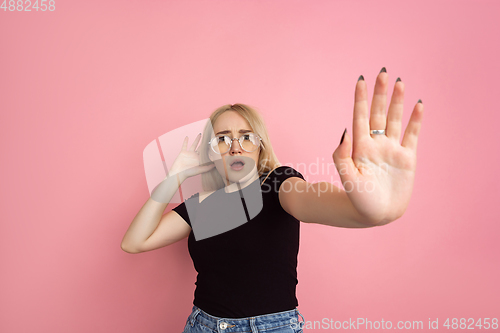 Image of Portrait of young caucasian woman with bright emotions on coral pink studio background