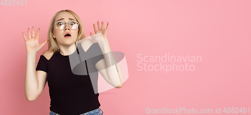 Image of Portrait of young caucasian woman with bright emotions on coral pink studio background