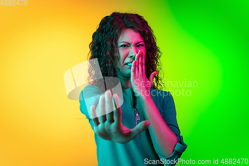 Image of African-american young woman\'s portrait isolated on gradient yellow-green background in neon light