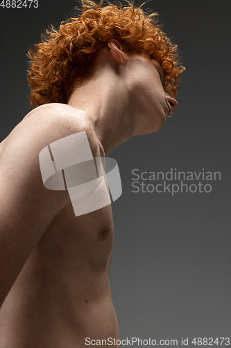 Image of Portrait of beautiful redhead man isolated on grey studio background. Concept of beauty, skin care, fashion and style