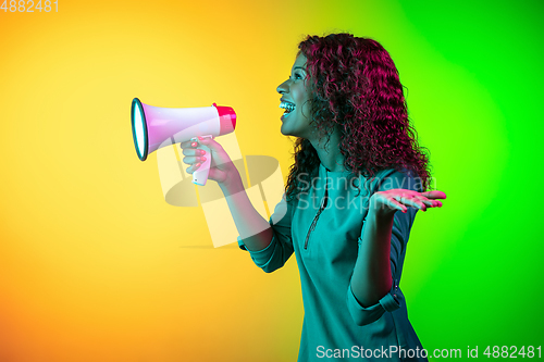 Image of African-american young woman\'s portrait isolated on gradient yellow-green background in neon light