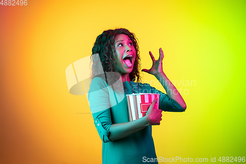 Image of African-american young woman\'s portrait isolated on gradient yellow-green background in neon light
