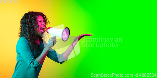 Image of African-american young woman\'s portrait isolated on gradient yellow-green background in neon light