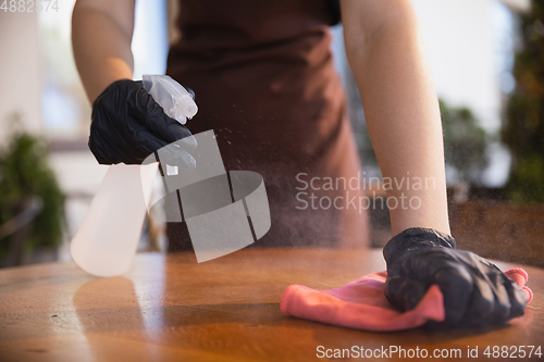 Image of The waitress works in a restaurant in a medical mask, gloves during coronavirus pandemic