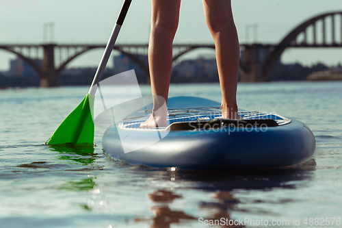 Image of Young attractive woman standing on paddle board, SUP. Active life, sport, leisure activity concept