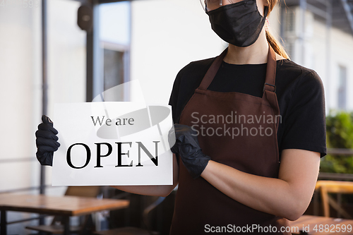 Image of The waitress works in a restaurant in a medical mask, gloves during coronavirus pandemic