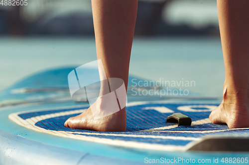 Image of Young attractive woman standing on paddle board, SUP. Active life, sport, leisure activity concept