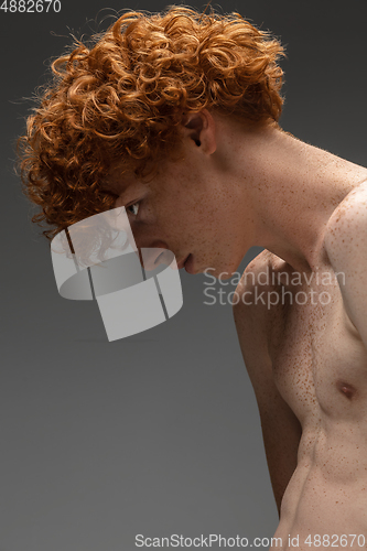 Image of Portrait of beautiful redhead man isolated on grey studio background. Concept of beauty, skin care, fashion and style