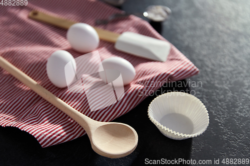 Image of eggs, flour, spoon, spatula, strainer and towel