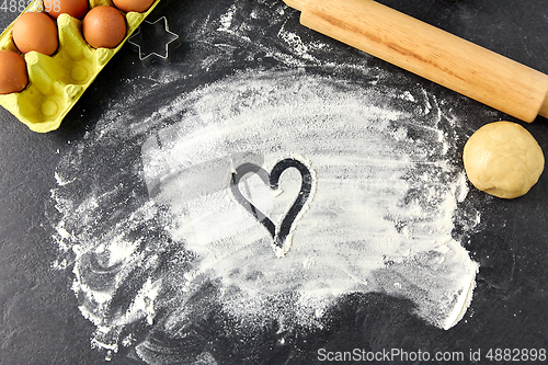 Image of heart on flour, rolling pin, eggs and dough