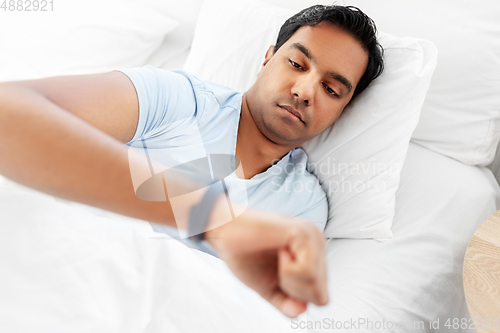 Image of indian man with health tracker in bed at home