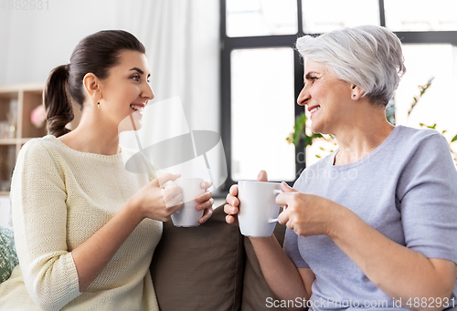 Image of senior mother and adult daughter drinking coffee