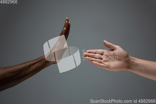 Image of Racial tolerance. Respect social unity. African and caucasian hands gesturing isolated on gray studio background