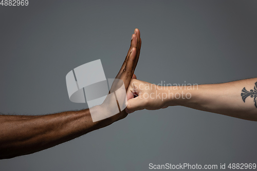 Image of Racial tolerance. Respect social unity. African and caucasian hands gesturing isolated on gray studio background