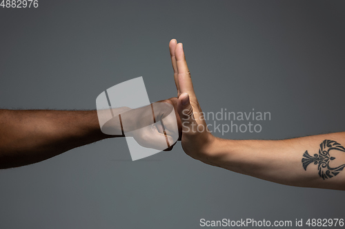 Image of Racial tolerance. Respect social unity. African and caucasian hands gesturing isolated on gray studio background