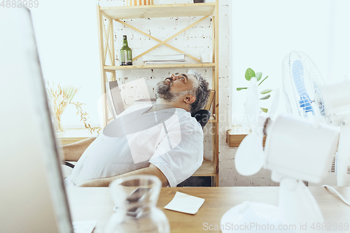 Image of Businessman, manager in office with computer and fan cooling off, feeling hot, flushed