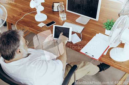 Image of Businessman, manager in office with computer and fan cooling off, feeling hot, flushed