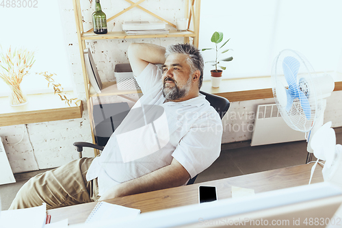 Image of Businessman, manager in office with computer and fan cooling off, feeling hot, flushed