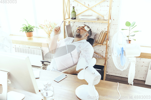 Image of Businessman, manager in office with computer and fan cooling off, feeling hot, flushed