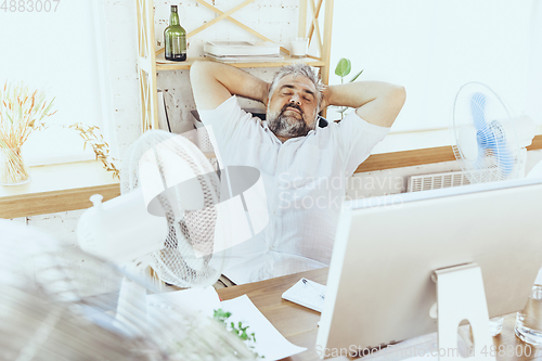 Image of Businessman, manager in office with computer and fan cooling off, feeling hot, flushed