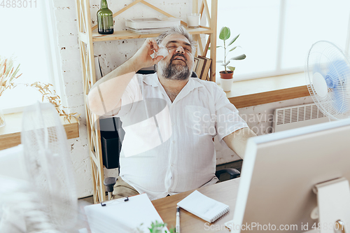 Image of Businessman, manager in office with computer and fan cooling off, feeling hot, flushed