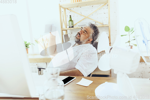 Image of Businessman, manager in office with computer and fan cooling off, feeling hot, flushed