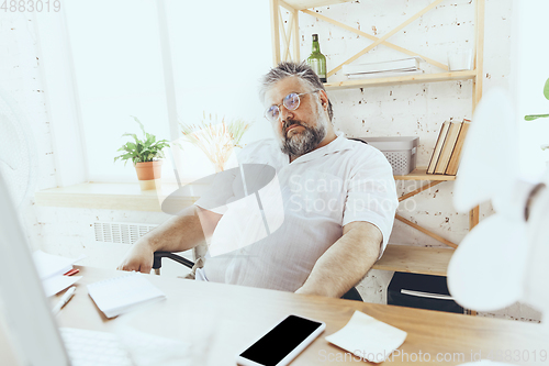 Image of Businessman, manager in office with computer and fan cooling off, feeling hot, flushed