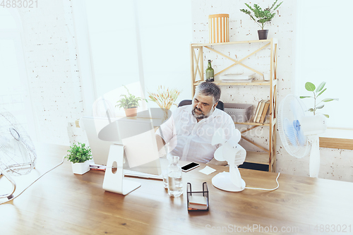 Image of Businessman, manager in office with computer and fan cooling off, feeling hot, flushed