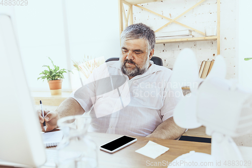 Image of Businessman, manager in office with computer and fan cooling off, feeling hot, flushed