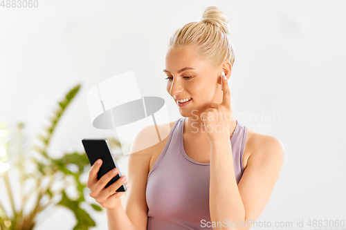 Image of woman with phone and earphones doing yoga at home