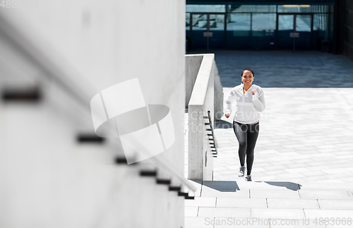 Image of african american woman running upstairs outdoors