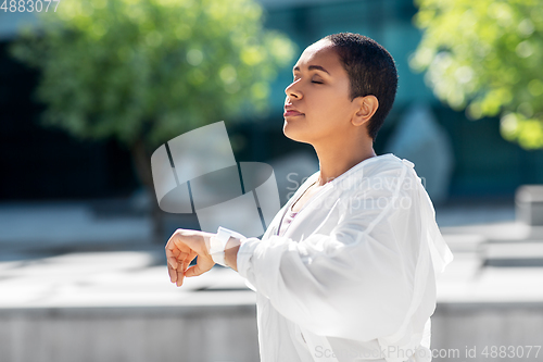 Image of young woman with smart watch breathing outdoors