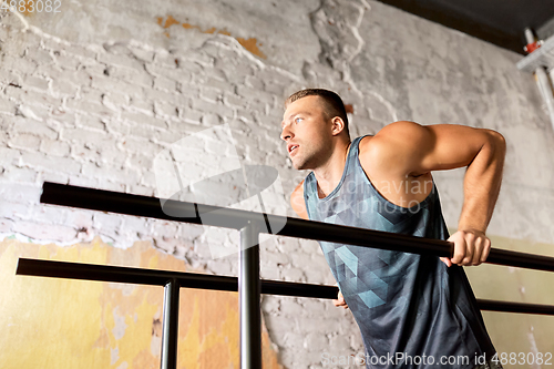 Image of man doing triceps dip on parallel bars in gym