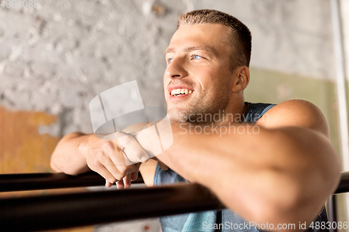 Image of smiling young man at parallel bars in gym