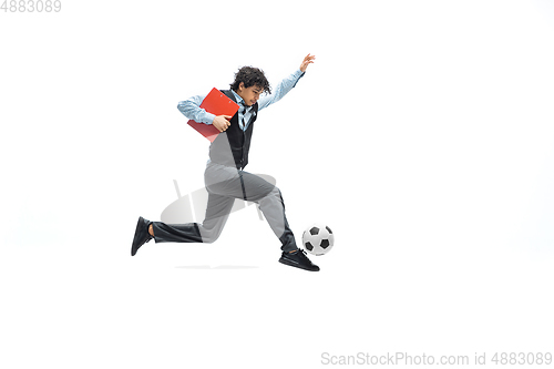 Image of Man in office clothes playing football or soccer with ball on white background. Unusual look for businessman in motion, action. Sport, healthy lifestyle.