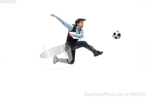 Image of Man in office clothes playing football or soccer with ball on white background. Unusual look for businessman in motion, action. Sport, healthy lifestyle.