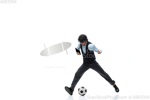 Image of Man in office clothes playing football or soccer with ball on white background. Unusual look for businessman in motion, action. Sport, healthy lifestyle.