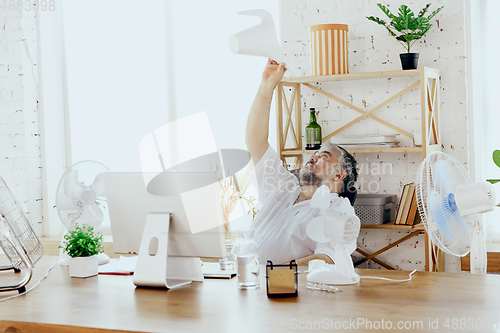 Image of Businessman, manager in office with computer and fan cooling off, feeling hot, flushed