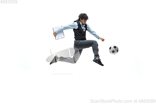 Image of Man in office clothes playing football or soccer with ball on white background. Unusual look for businessman in motion, action. Sport, healthy lifestyle.