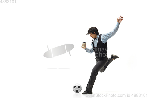 Image of Man in office clothes playing football or soccer with ball on white background. Unusual look for businessman in motion, action. Sport, healthy lifestyle.