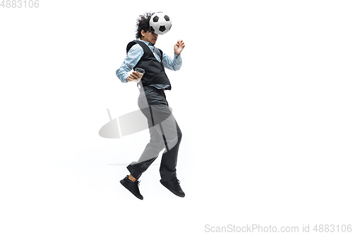 Image of Man in office clothes playing football or soccer with ball on white background. Unusual look for businessman in motion, action. Sport, healthy lifestyle.