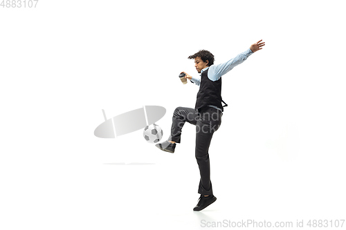 Image of Man in office clothes playing football or soccer with ball on white background. Unusual look for businessman in motion, action. Sport, healthy lifestyle.