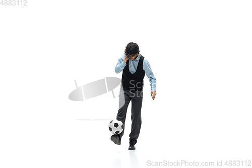 Image of Man in office clothes playing football or soccer with ball on white background. Unusual look for businessman in motion, action. Sport, healthy lifestyle.