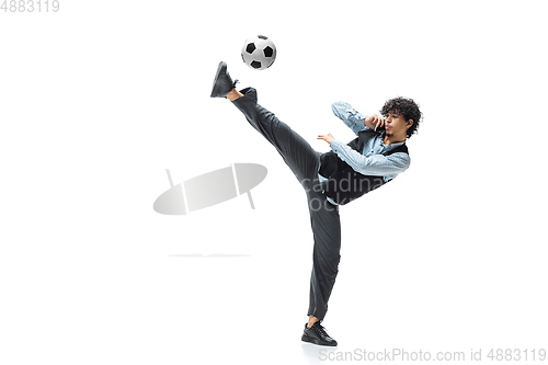 Image of Man in office clothes playing football or soccer with ball on white background. Unusual look for businessman in motion, action. Sport, healthy lifestyle.