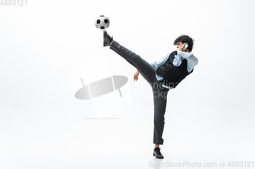 Image of Man in office clothes playing football or soccer with ball on white background. Unusual look for businessman in motion, action. Sport, healthy lifestyle.